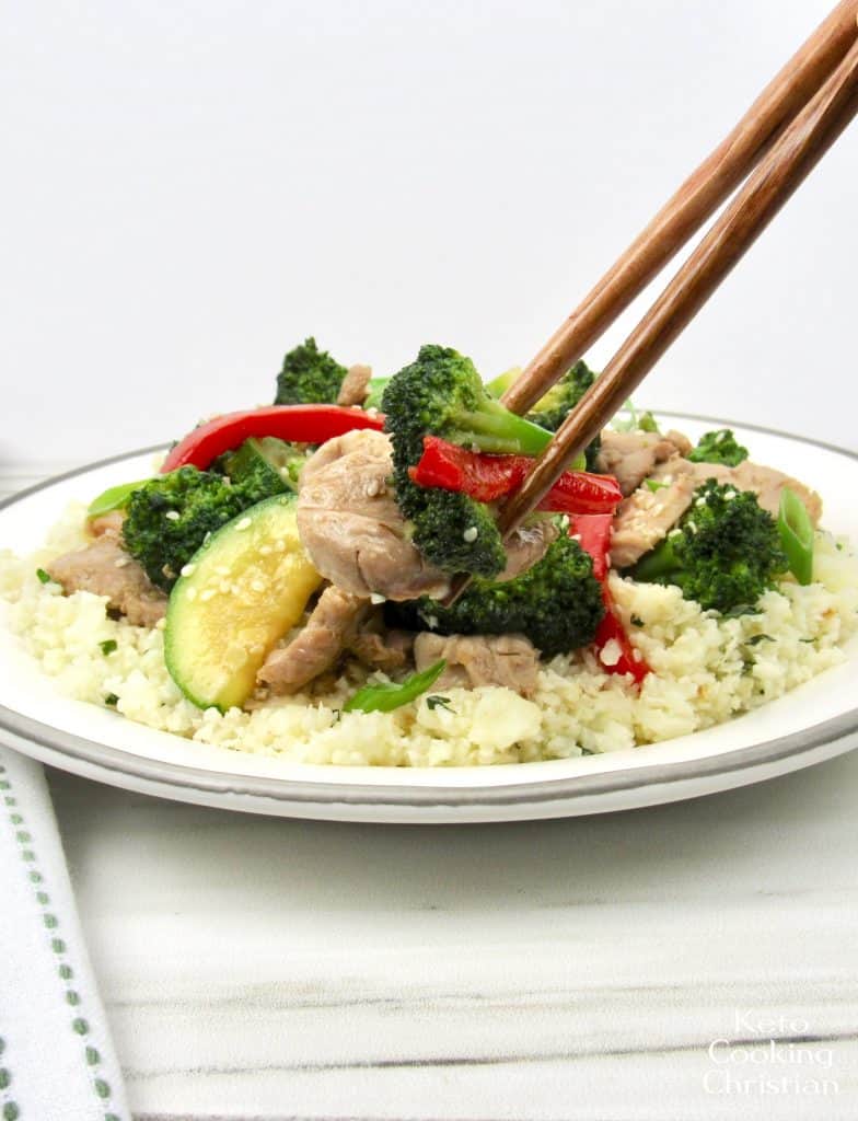 plate of pork and veggies with chop sticks