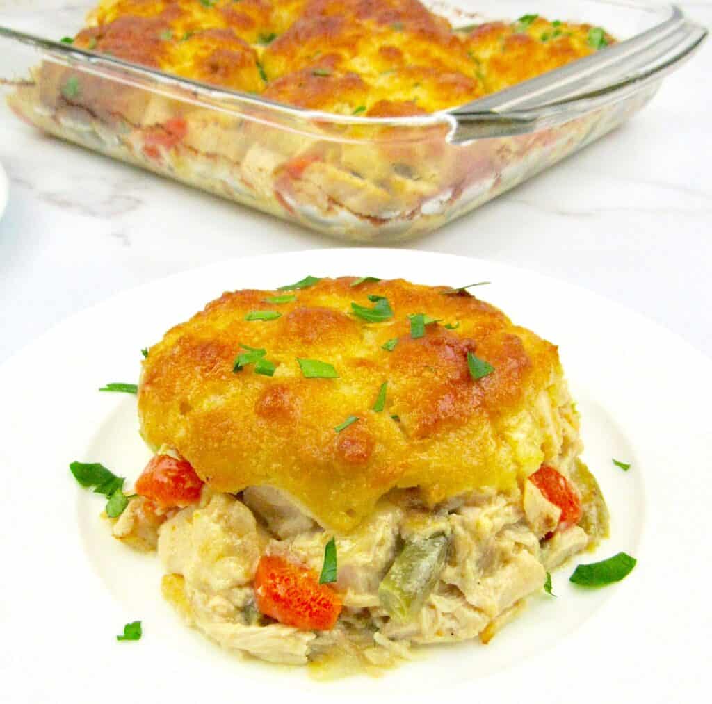 piece of chicken pot pie casserole on white plate with casserole in the background