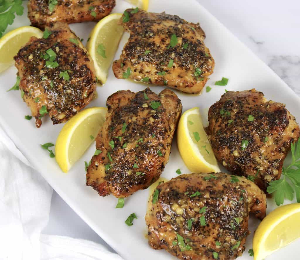 overhead view of 6 pieces of lemon chicken on white plate with lemon wedges