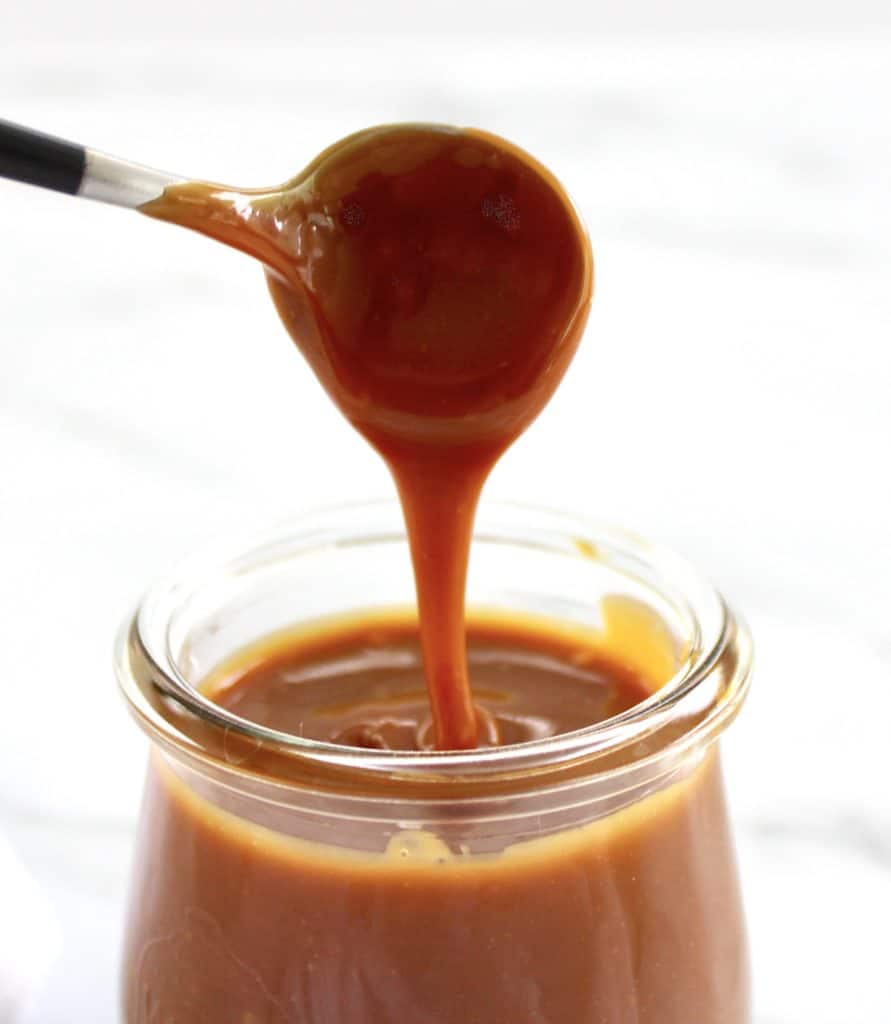caramel sauce being spooned out of jar