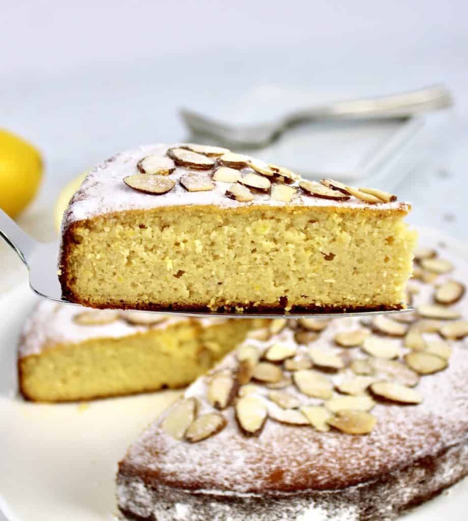 closeup of lemon ricotta cake slice being held up in front of cake