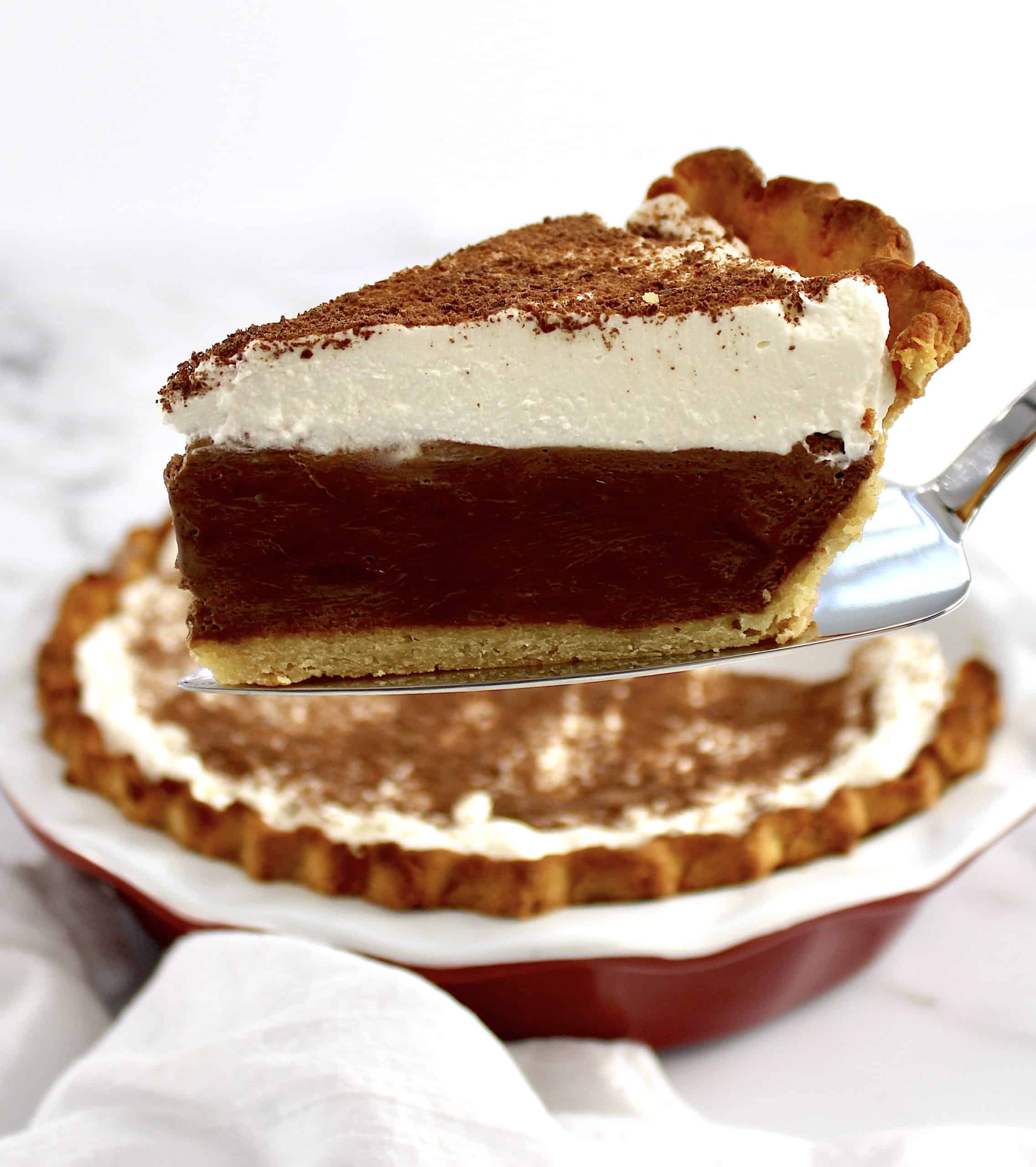 slice of french silk pie on pie server with whip cream on top