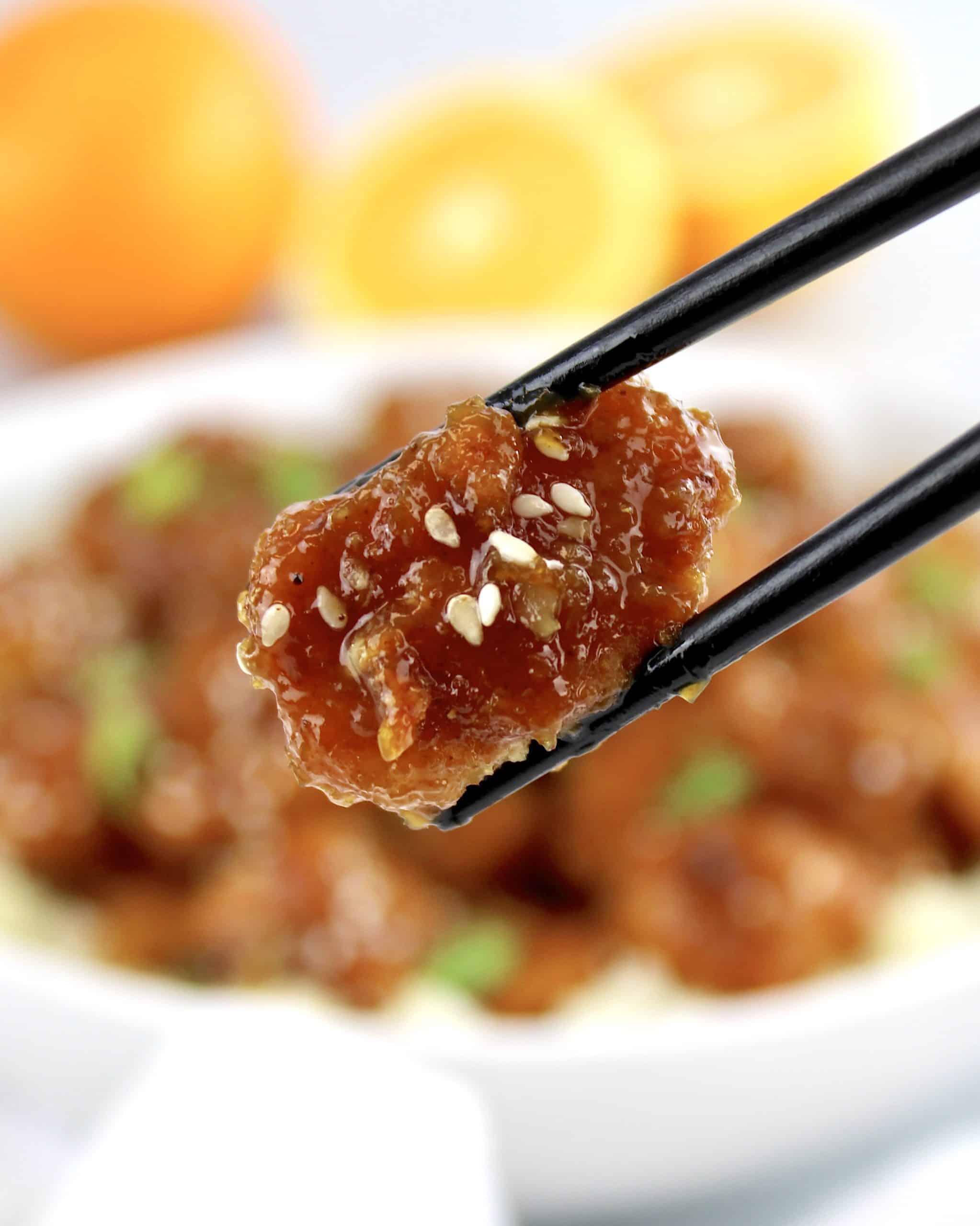 orange chicken with chopstick holding up a piece