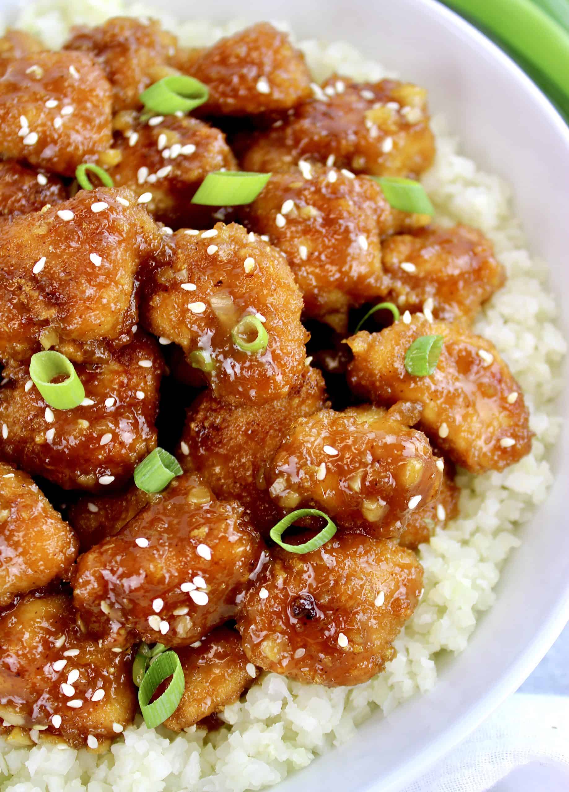 orange chicken over cauliflower rice with scallions on top