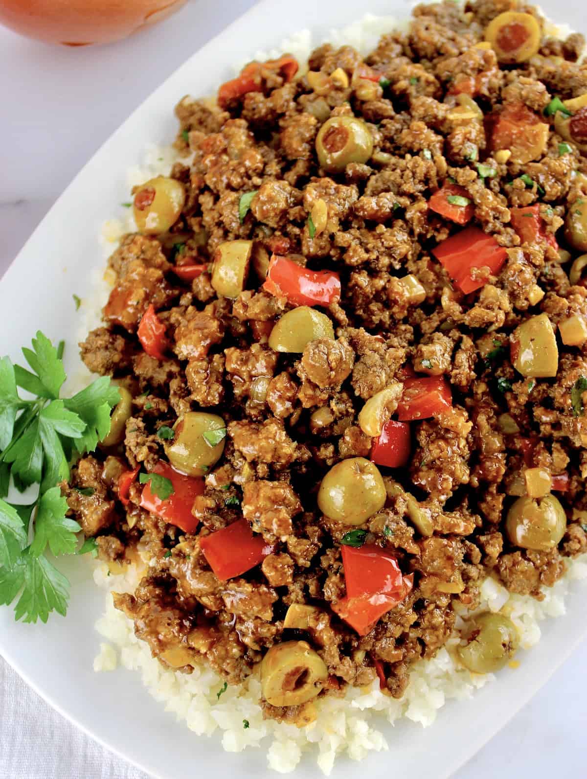 Keto picadillo over cauliflower rice on white plate with parsley garnish