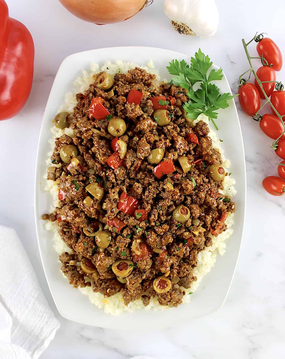 overhead view of Keto picadillo over cauliflower rice on white plate with parsley garnish