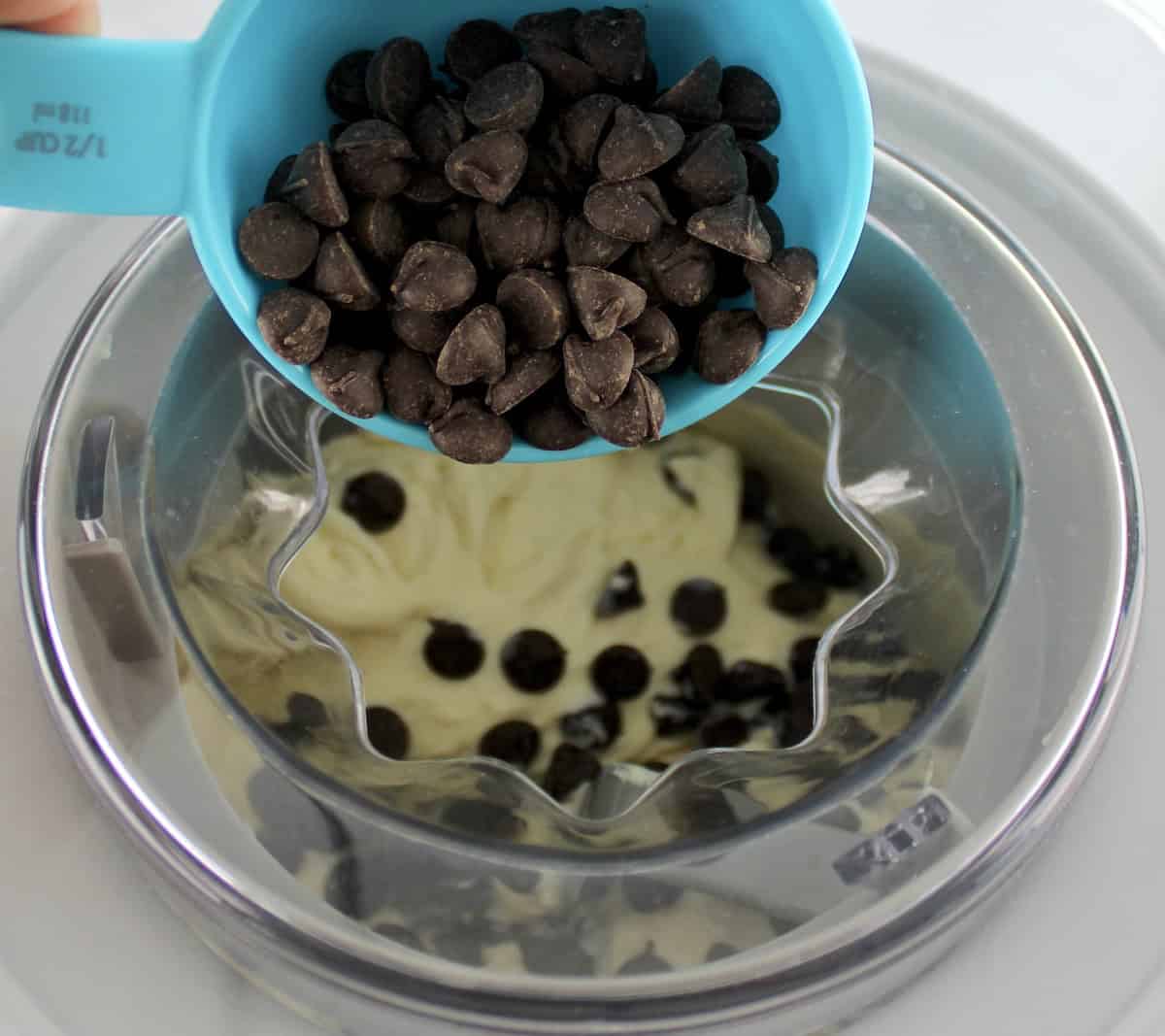 chocolate chips being poured into Vanilla Ice Cream in ice cream maker